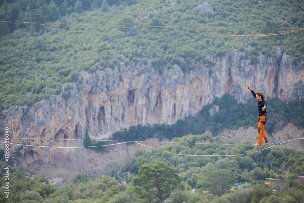 Obraz premium A tightrope walker walks along a cable stretched over a canyon.