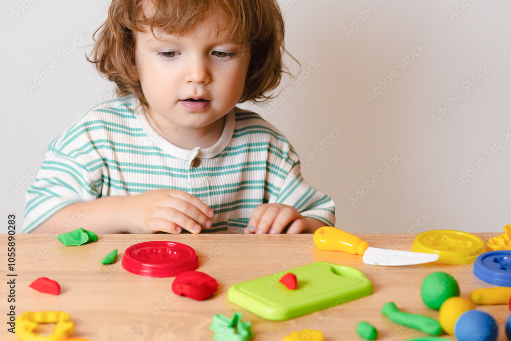 Cute little boy playing at home, molding multi-colored plasticine. Toddler sculpts with clay stucco Cute little boy playing at home, molding multi-colored plasticine. Toddler sculpts with clay stucco
