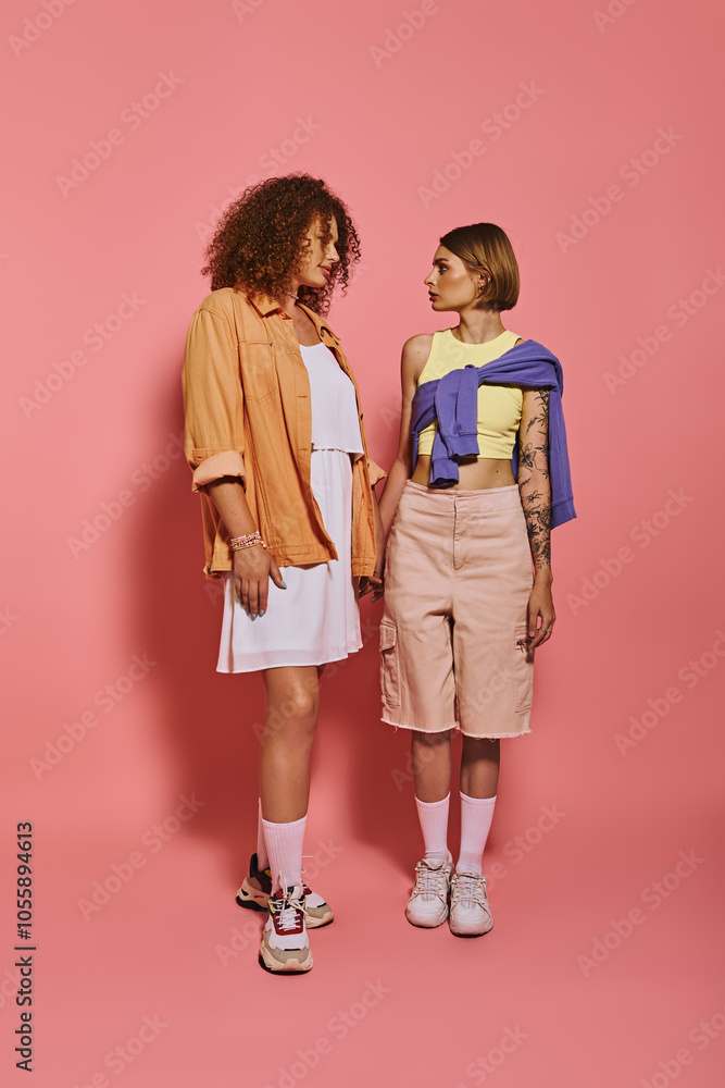 Fototapeta premium A joyful couple celebrates their love in a stylish studio adorned with a pink backdrop.