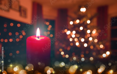 Burning red Advent candle isolated on glowing Christmas tree background.