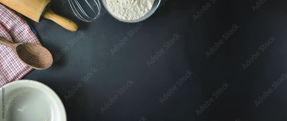 Fototapeta premium Escena para fondo de tarjeta. Fondo de pizarra negra. Elementos de cocina. Harina y uslero para hacer pan