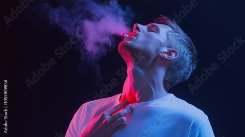 A young man exhales smoke while enjoying a moment of reflection in a dimly lit environment with colorful lighting