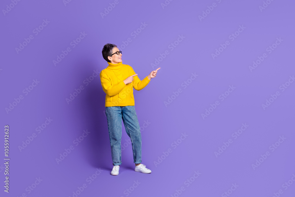 Full length photo of cheerful pretty lady dressed knitted jumper looking pointing two fingers empty space isolated purple color background Full length photo of cheerful pretty lady dressed knitted jumper looking pointing two fingers empty space isolated purple color background