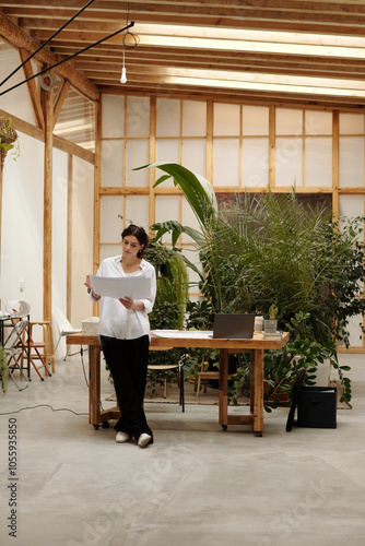 Architect gesturing while presenting in spacious, modern workspace adorned with lush green plants photo