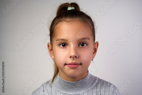 Close-up portrait of a child girl with brown eyes and hairs, looking at camera, white background.