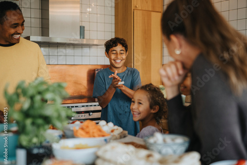 Happy boy applauding sister helping family in preparing food at home photo