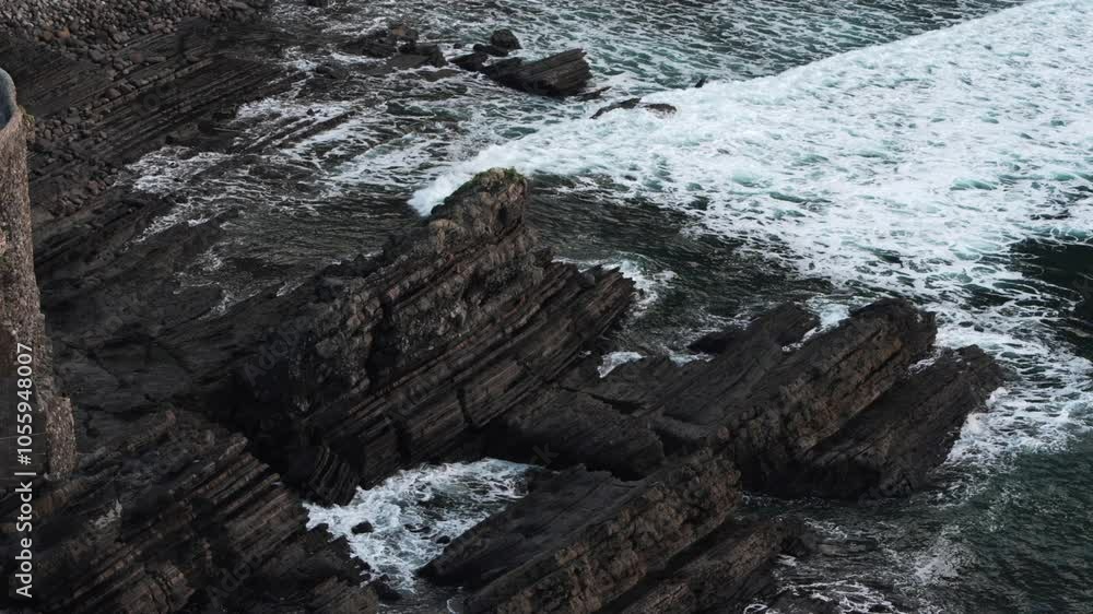 This stunning aerial video highlights a dramatic rocky coastline where waves crash against the rocks. A lighthouse atop a cliff overlooks a serene yet powerful natural landscape This stunning aerial video highlights a dramatic rocky coastline where waves crash against the rocks. A lighthouse atop a cliff overlooks a serene yet powerful natural landscape