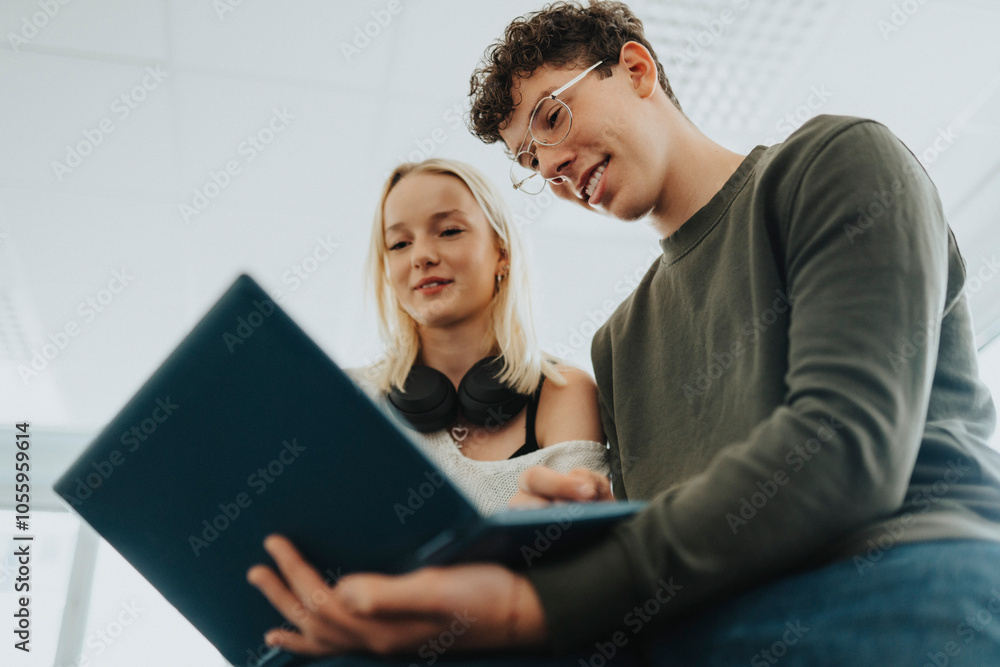 Smiling teenage boy and girl using laptop in classroom Smiling teenage boy and girl using laptop in classroom