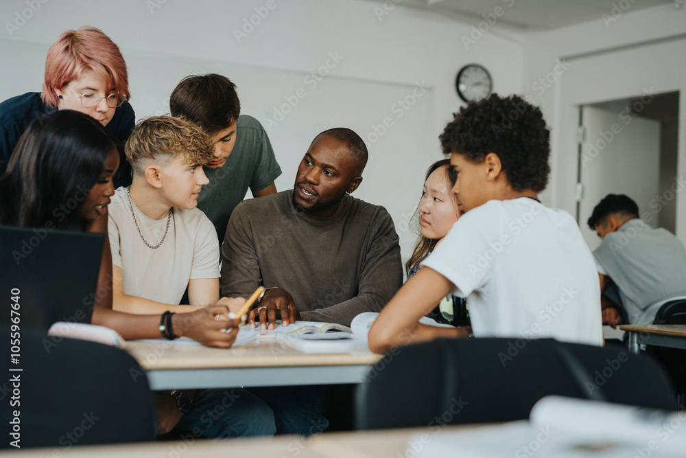 Male teacher teaching boys and girls with non-binary person in classroom Male teacher teaching boys and girls with non-binary person in classroom