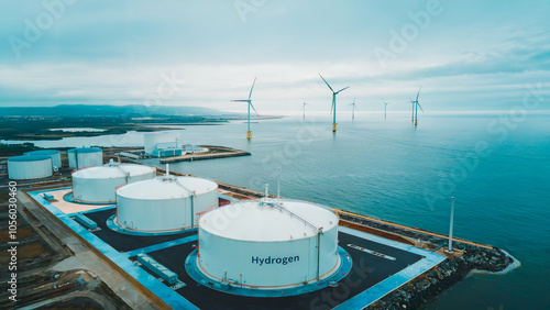 An overhead perspective of a coastal hydrogen storage site, highlighting storage tanks and renewable energy infrastructure supported by offshore wind turbines. photo