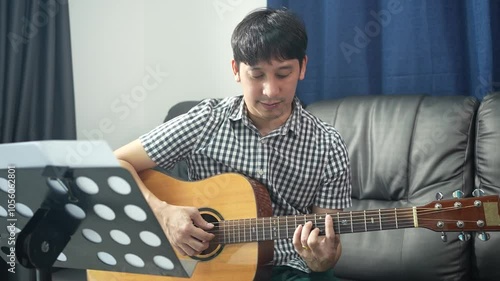 A middle-aged man was playing his favorite song on the guitar.