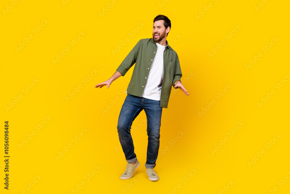 Full size photo of nice young man good mood dancing wear shirt isolated on yellow color background Full size photo of nice young man good mood dancing wear shirt isolated on yellow color background