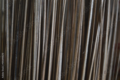 Close-up of a textured stack of coconut palm fronds (lidi), showcasing the natural fibers and earthy tones of the dried leaves. photo