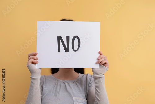 Woman holding sign with the word "No". Ability to refuse and say no. Yellow background 