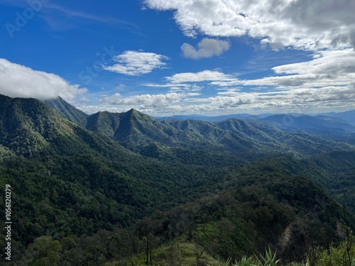 A breathtaking view of rolling mountains under a blue sky adorned with clouds, capturing the beauty of nature in a serene landscape