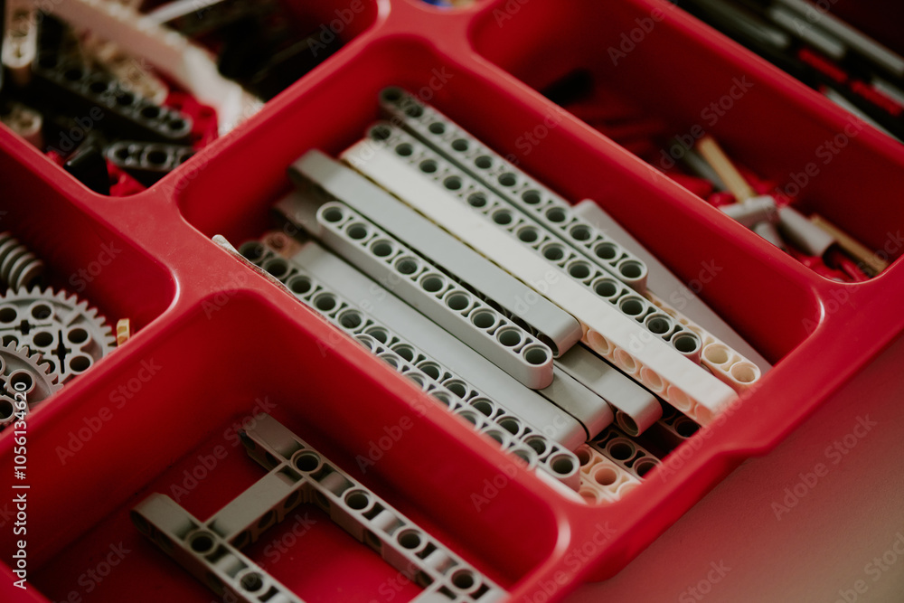 Medium close up of gray spare parts in red plastic cell of container Medium close up of gray spare parts in red plastic cell of container