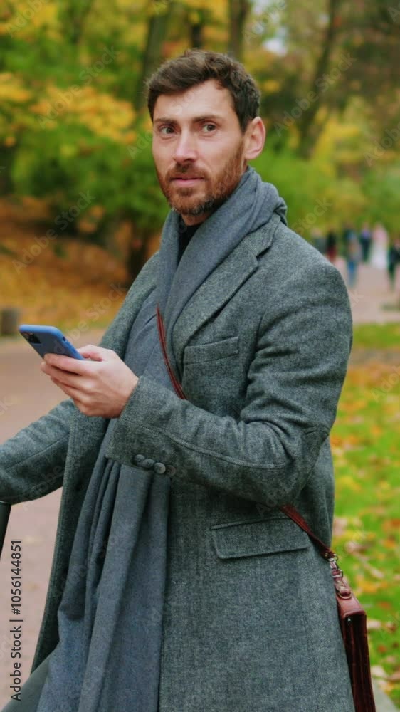 In autumn park stylish man use phone stand with electric scooter. Ecological transportation. Feel happy smiling. Urban outdoors. Slow motion In autumn park stylish man use phone stand with electric scooter. Ecological transportation. Feel happy smiling. Urban outdoors. Slow motion