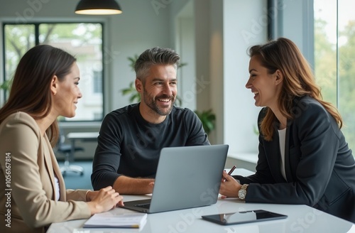 Wallpaper Mural Three professionals engaged in a lively discussion around a laptop in a modern office setting during the daytime Torontodigital.ca