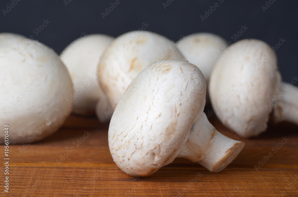 Fresh champignon mushrooms close-up on a kitchen wooden board, frontal view, detail, cooking, healthy food, diet Fresh champignon mushrooms close-up on a kitchen wooden board, frontal view, detail, cooking, healthy food, diet