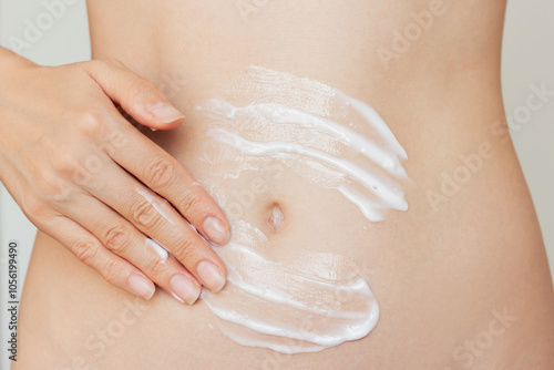 Tableau sur toile Close up young woman applying a white moisturizing and nourishing cream to the skin of her slim stomach from stretch marks