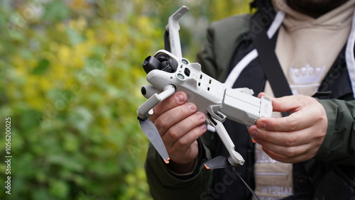 A man holds a drone and a battery in his hands