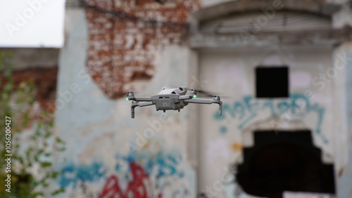 A drone in the sky next to a ruined, abandoned building