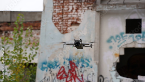 A drone in the sky next to a ruined, abandoned building