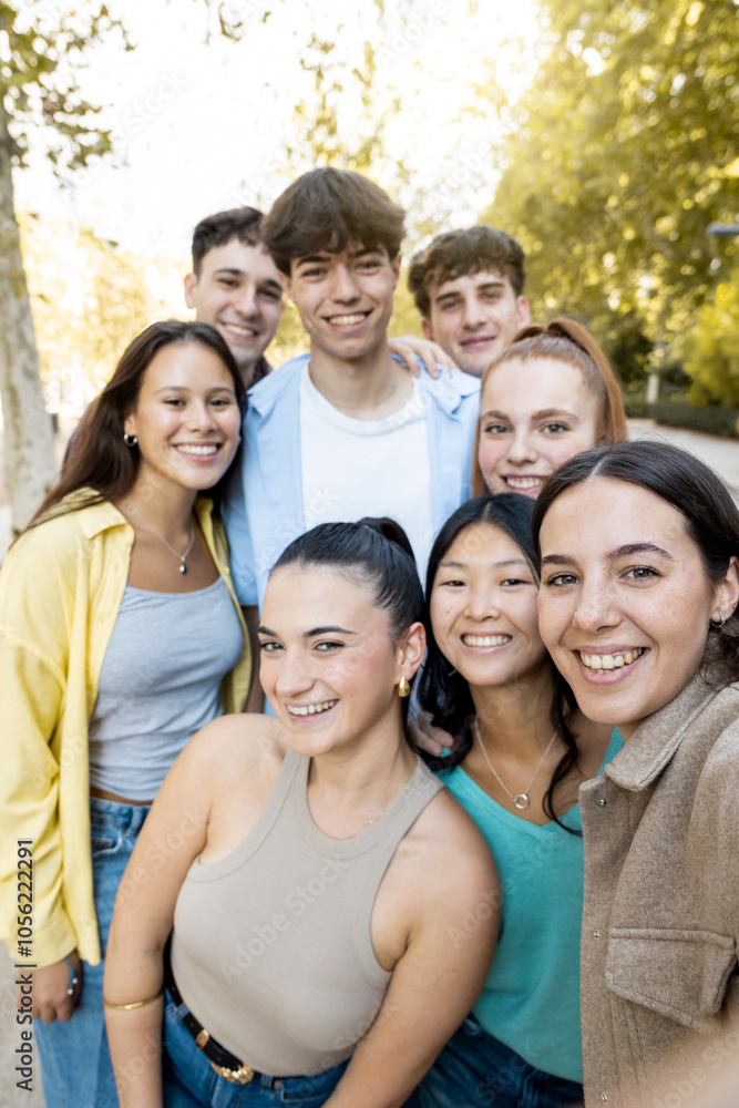 A group of 8 20-year-olds of different ethnicities have fun in the city in the afternoon.The boys take a vertical photograph with their mobile phone.Concept of youth groups. A group of 8 20-year-olds of different ethnicities have fun in the city in the afternoon.The boys take a vertical photograph with their mobile phone.Concept of youth groups.