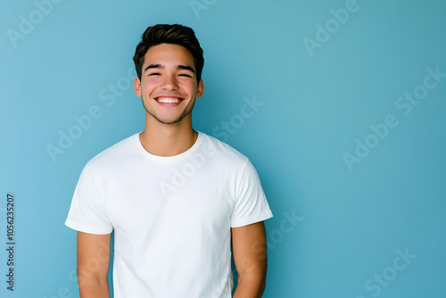 Young man in a casual white t-shirt, smiling on a plain blue background. high quality