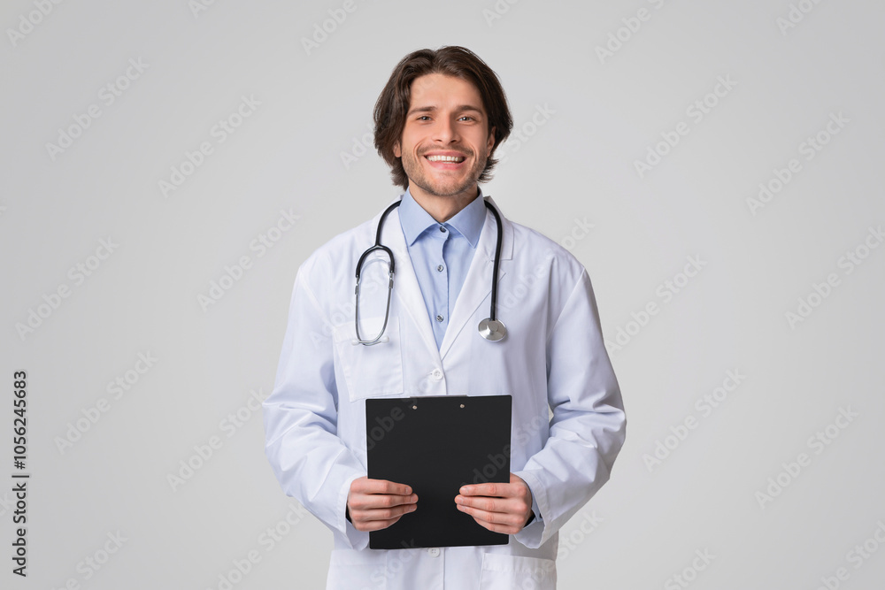 Portrait Of Smiling Male Therapist Posing With Clipboard In Hands Over Light Studio Background, Copy Space Portrait Of Smiling Male Therapist Posing With Clipboard In Hands Over Light Studio Background, Copy Space