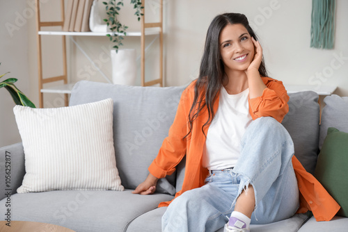 Pretty young woman sitting on comfy sofa at home