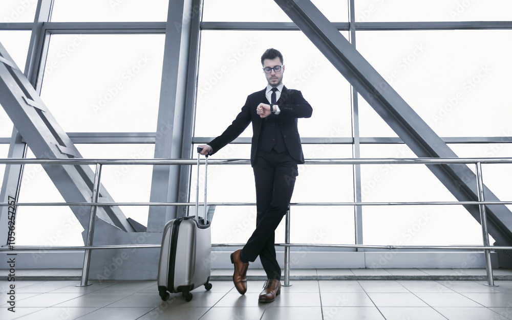 Business Travel. Confident Manager In Specs With Suitcase Checking Time Looking At Wristwatch Standing At Airport Business Travel. Confident Manager In Specs With Suitcase Checking Time Looking At Wristwatch Standing At Airport