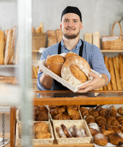 Authors bakery, family business idea. Sales consultant holds loaf bread in towel hemstitched serviette, shows product, offers to choose fresh buns. photo