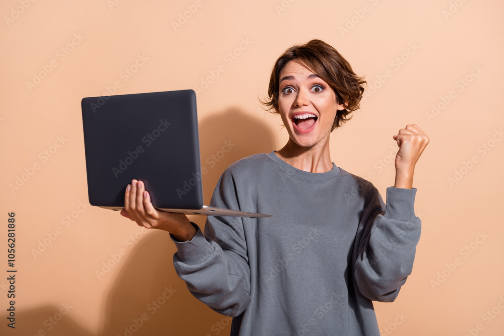 © deagreez - Portrait of satisfied crazy girl with short hairdo wear oversize pullover hold laptop yell win bet isolated on beige color background © deagreez - Portrait of satisfied crazy girl with short hairdo wear oversize pullover hold laptop yell win bet isolated on beige color background