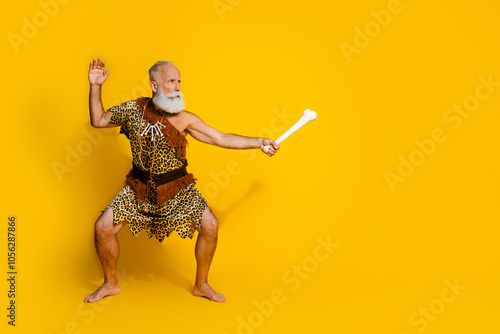 Full length photo of cool wildman dressed leopard skin fighting mammoth bone mockup space isolated yellow color background photo