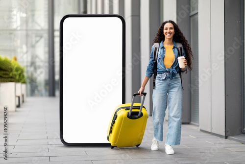 A woman with curly hair strolls through a sleek city environment, pulling a yellow suitcase behind her while holding a coffee cup. The atmosphere is contemporary and vibrant. photo