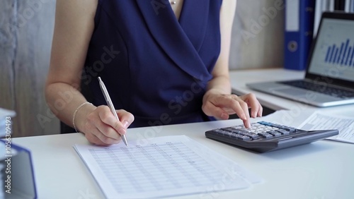 Wallpaper Mural Businesswoman with dark blue dress is using dark calculator and taking notes of company expenses in her office. Taxes and audit in business Torontodigital.ca