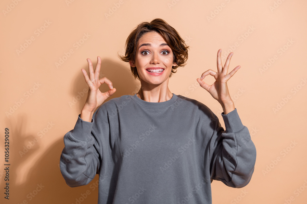 Photo portrait of attractive young woman show double okey impressed dressed stylish gray clothes isolated on beige color background Photo portrait of attractive young woman show double okey impressed dressed stylish gray clothes isolated on beige color background