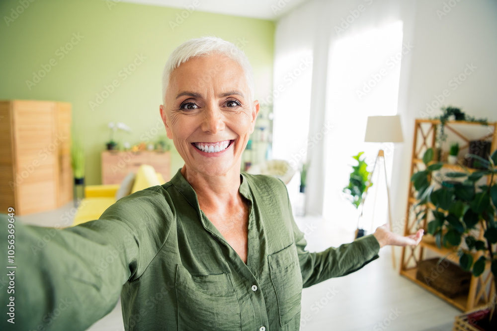 Photo of pretty cheerful lady wear green shirt recording video vlog showing apartment indoors room home house