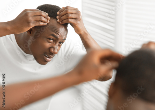 Dandruff Problem. Worried African American Man Looking At Flaky Scalp In Mirror, Touching Head Examining Gray Hair And Hairloss Issue Standing In Bathroom At Home. Men's Beauty And Haircare Treatment