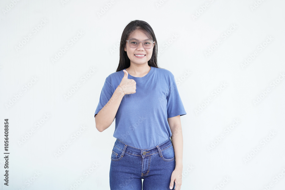 Beautiful Asian woman smiles warmly, giving a thumbs-up gesture to convey approval against a white background Beautiful Asian woman smiles warmly, giving a thumbs-up gesture to convey approval against a white background