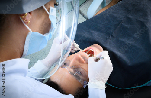 A dentist conducts an oral examination on a patient in a contemporary dental clinic, focusing on safety with protective gear during the procedure.