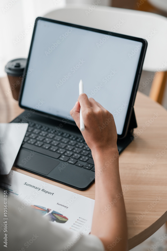A person interacts with a tablet using a stylus, accompanied by a keyboard and coffee cup, in a contemporary workspace setting. A person interacts with a tablet using a stylus, accompanied by a keyboard and coffee cup, in a contemporary workspace setting.