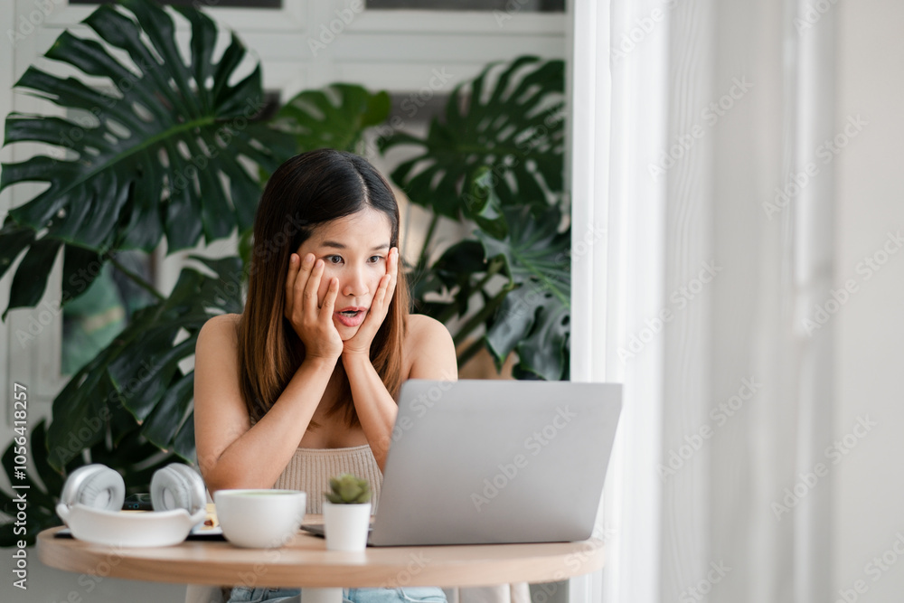 Young woman with surprised expression using laptop at home, surrounded by lush green plants and natural light. Young woman with surprised expression using laptop at home, surrounded by lush green plants and natural light.
