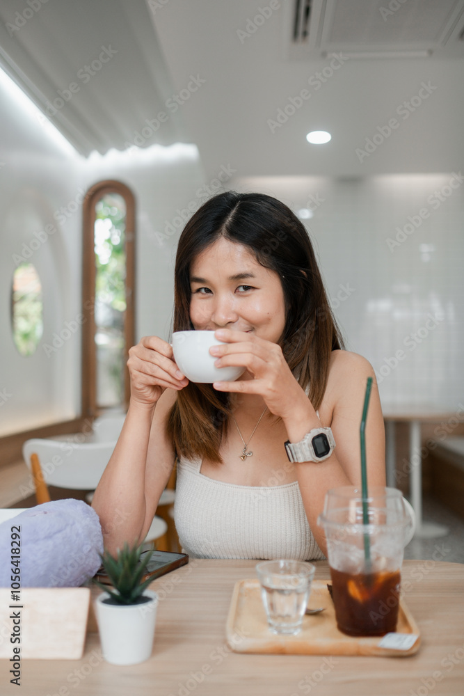 Young woman sipping coffee in a stylish cafe, showcasing modern interior design and a cozy ambiance. Young woman sipping coffee in a stylish cafe, showcasing modern interior design and a cozy ambiance.