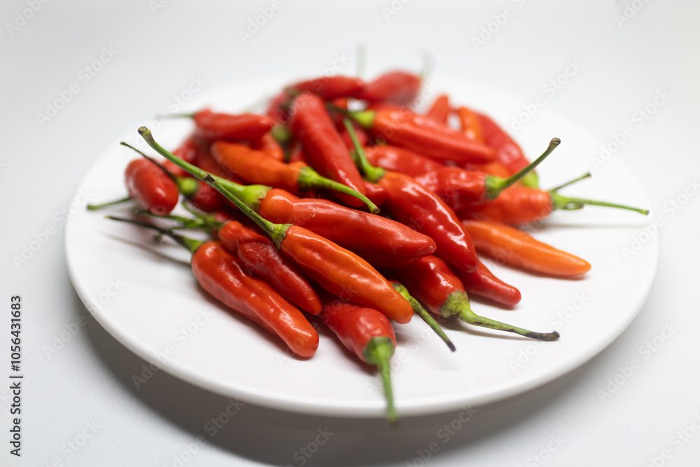 Fresh red chili peppers arranged on a white plate. Fresh red chili peppers arranged on a white plate.