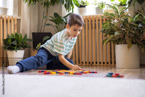 Fotografie A European boy plays on the floor with construction set