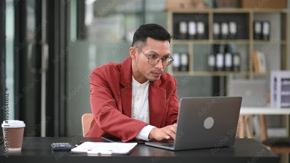 Young man using laptop and tablet while sitting at her working place. Concentrated at work. Young man using laptop and tablet while sitting at her working place. Concentrated at work.