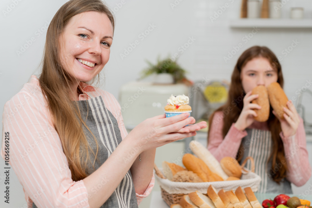 Portrait of smiling mother showing cupcake, mom baking bakery with daughter. happy family time Portrait of smiling mother showing cupcake, mom baking bakery with daughter. happy family time