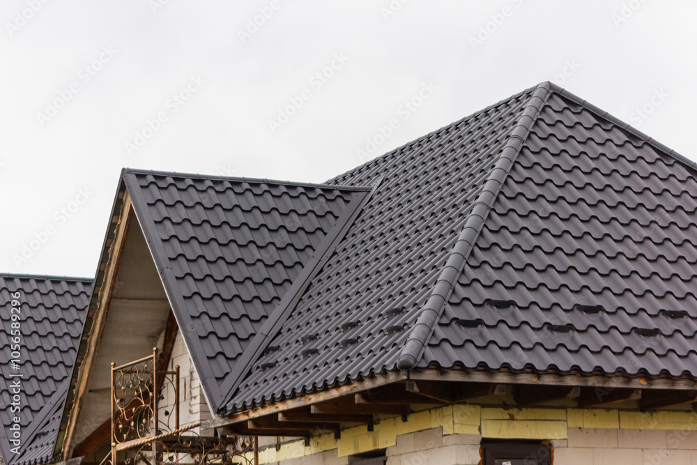 Covering the house with metal tiles. Close-up of the slope of the roof. Covering the house with metal tiles. Close-up of the slope of the roof.